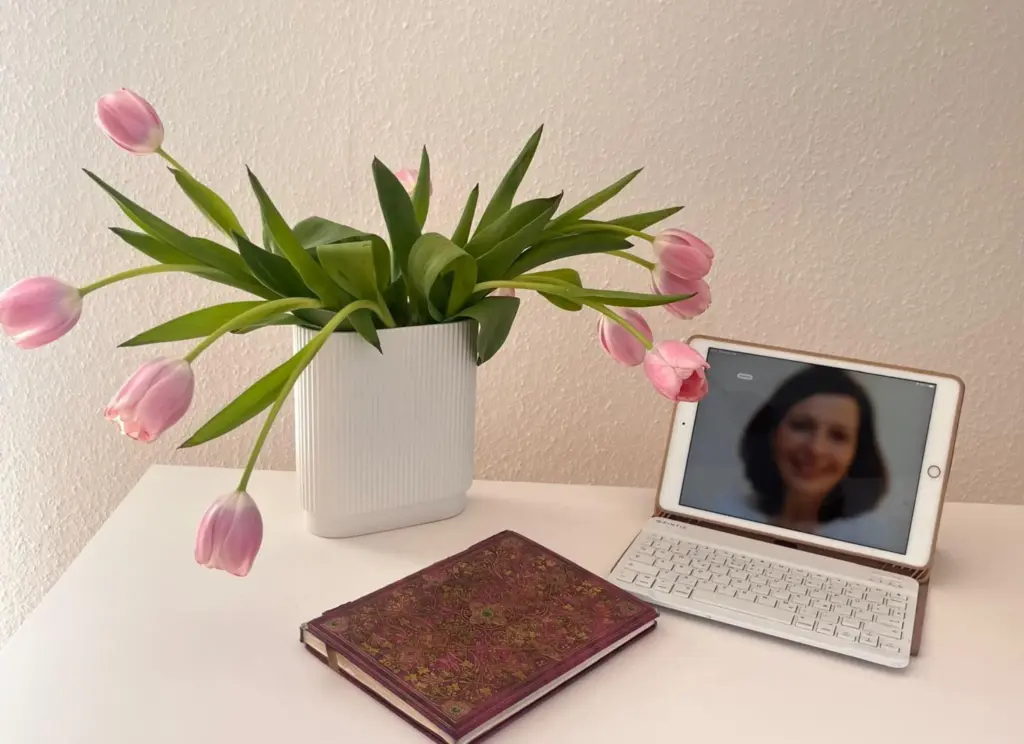 Ein Tisch mit einem Tablet, einem Buch und einem Strauß Tulpen
